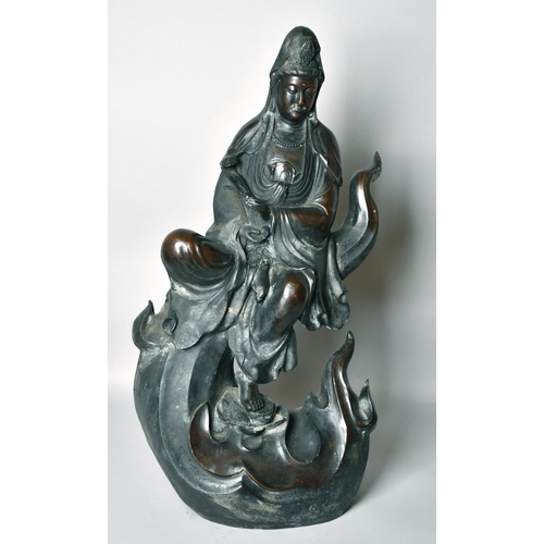 1221 - A LARGE CHINESE BRONZE FIGURE OF GUANVIN sitting atop a wave, holding a sceptre, bearing a six-chara... 