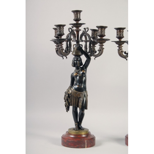 1233 - A VERY GOOD PAIR OF BRONZE AND GILDED BRONZE NUBIAN FIGURE FIVE-LIGHT CANDELABRA, each with four scr... 