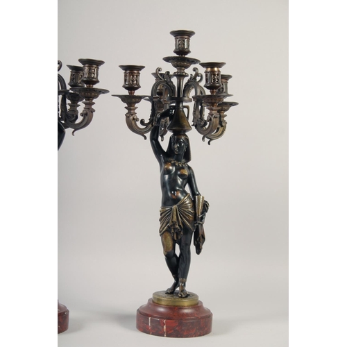 1233 - A VERY GOOD PAIR OF BRONZE AND GILDED BRONZE NUBIAN FIGURE FIVE-LIGHT CANDELABRA, each with four scr... 