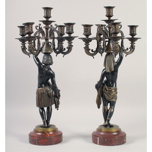 1233 - A VERY GOOD PAIR OF BRONZE AND GILDED BRONZE NUBIAN FIGURE FIVE-LIGHT CANDELABRA, each with four scr... 