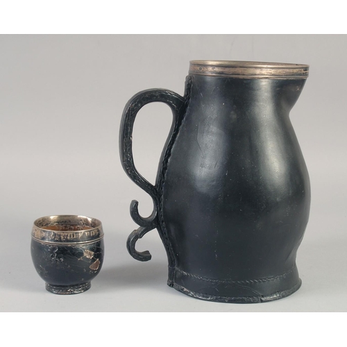 1243 - A BLACK LEATHER JUG with silver mounts and scroll handle, 14.5ins high, plus an associated silver mo... 