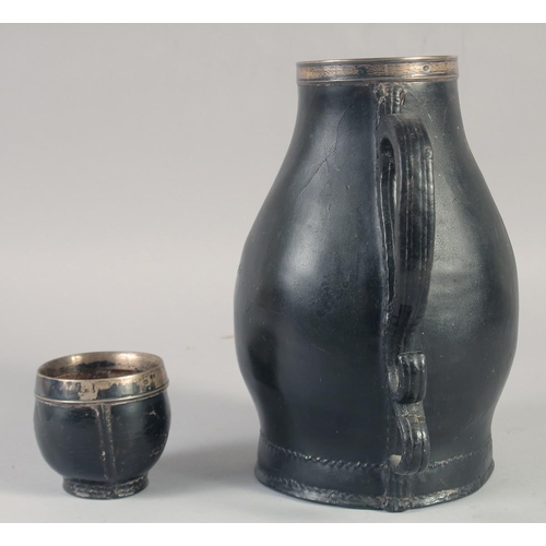 1243 - A BLACK LEATHER JUG with silver mounts and scroll handle, 14.5ins high, plus an associated silver mo... 