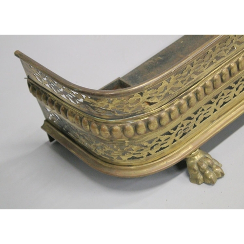 1311 - A REGENCY PIERCED BRASS FENDER with pierced decoration supported on three cast brass claw feet. 3ft ... 