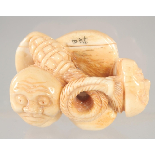 1416 - A CARVED BONE FACES NETSUKE.