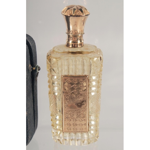 1442 - A CUT GLASS SCENT BOTTLE WITH HINGED GOLD TOP, cased. 9cm high.