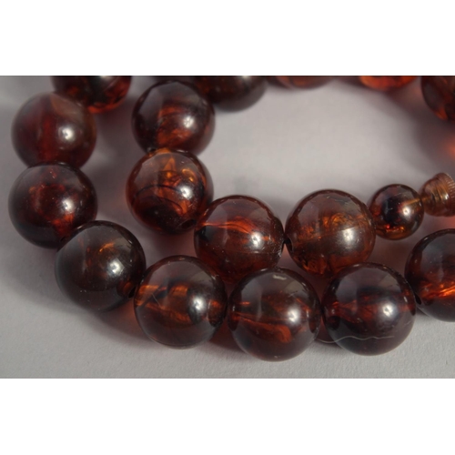 1570 - AN AMBER NECKLACE with twenty one ball beads. 15ins long.