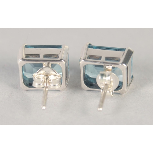 1584 - A PAIR OF SILVER EMERALD CUT BLUE TOPAZ STUDS.