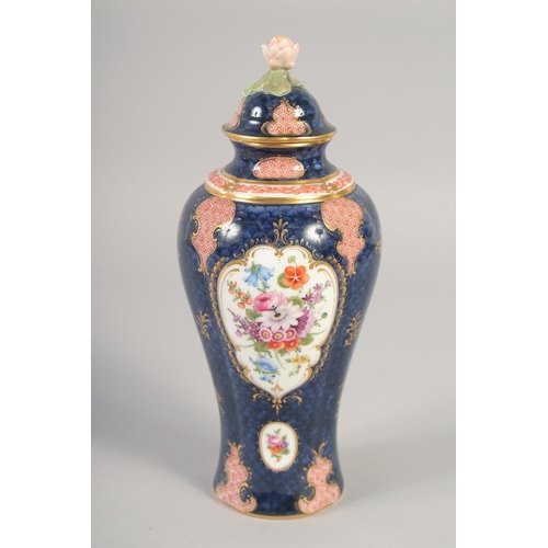 1090 - A ROYAL WORCESTER VASE AND COVER painted with flowers on a blue scale ground with red cell panels by... 