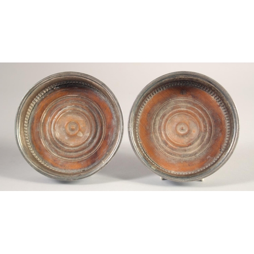 1700 - A PAIR OF GEORGE III CIRCULAR PLATED WINE COASTERS and turned wood bases. 5.25ins diameter.