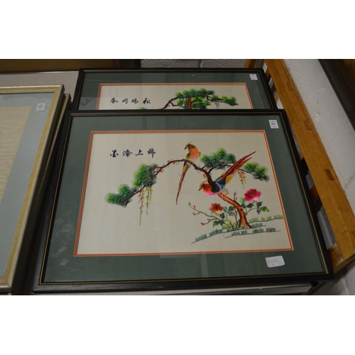 461 - A pair of colourful Chinese embroidered pictures depicting exotic birds on branches.