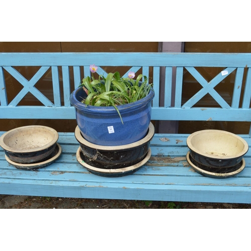 13 - A blue glazed plant pot with plants and a set of three black glazed planters with bases.