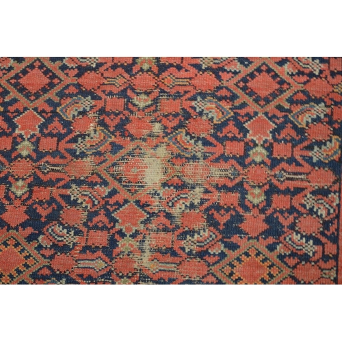 363 - A Persian carpet, red ground with stylised decoration, worn and damaged 185cm x 130cm.