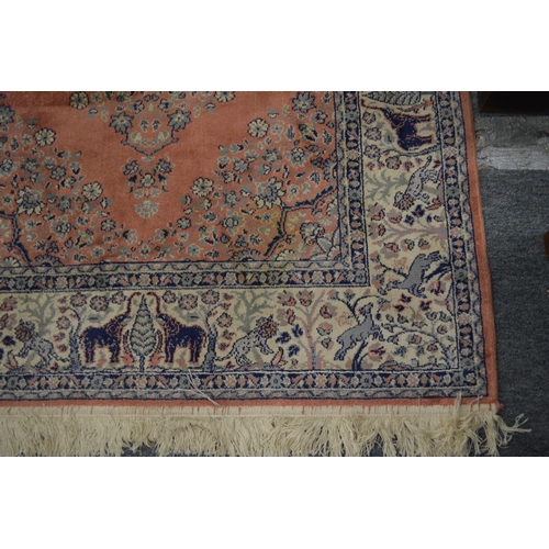 372 - A pink ground Indian rug, the border decorated with elephants 140cm x 100cm.