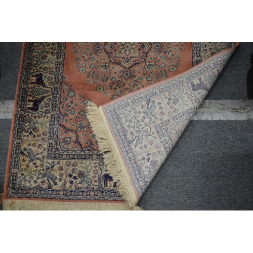 372 - A pink ground Indian rug, the border decorated with elephants 140cm x 100cm.