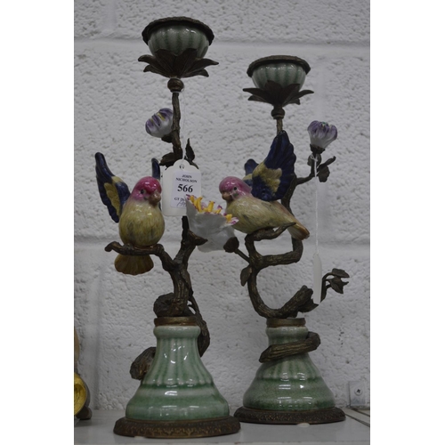 566 - A pair of decorative pottery and brass candlesticks modelled as birds on branches.