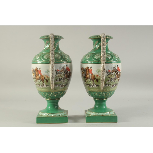 1151 - A PAIR OF SEVRES DESIGN GREEN GROUND HUNTING VASES with looped handles on square bases.