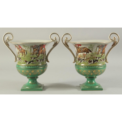 1152 - A PAIR OF SEVRES DESIGN GREEN GROUND, TWO HANDLED URN SHAPED HUNTING SCENES VASES. 11ins high.