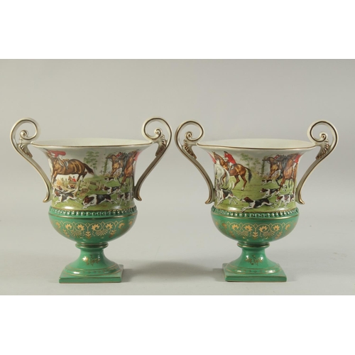 1152 - A PAIR OF SEVRES DESIGN GREEN GROUND, TWO HANDLED URN SHAPED HUNTING SCENES VASES. 11ins high.