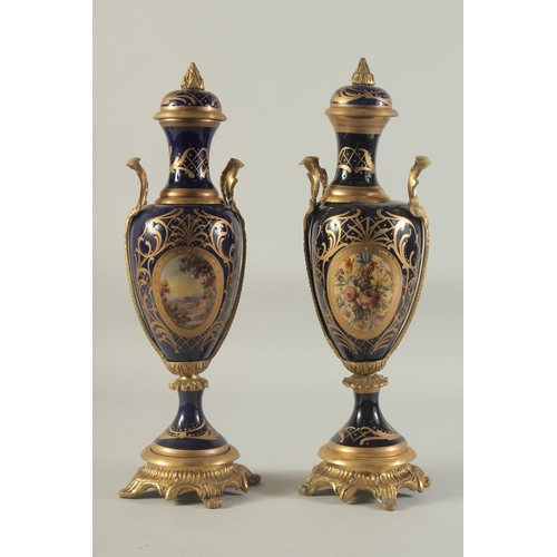 1153 - A PAIR OF SEVRES DESIGN DEEP BLUE PORCELAIN AND GILT METAL VASES AND STANDS. 18ins high.