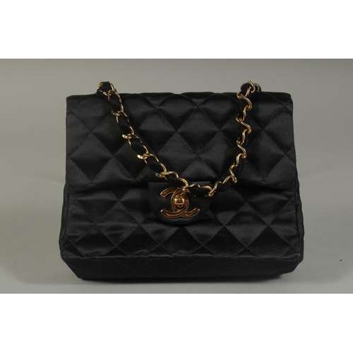 1321 - A SMALL CHANEL PADDED BLACK EVENING BAG 6.5ins long with entwined gilt metal and leather chain, 20in... 