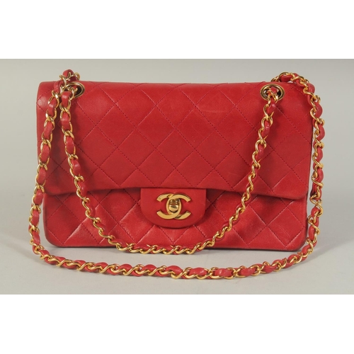 1344 - A CHANEL PADDED LEATHER RED HANDBAG, with entwined leather and gilt straps. 9ins wide.