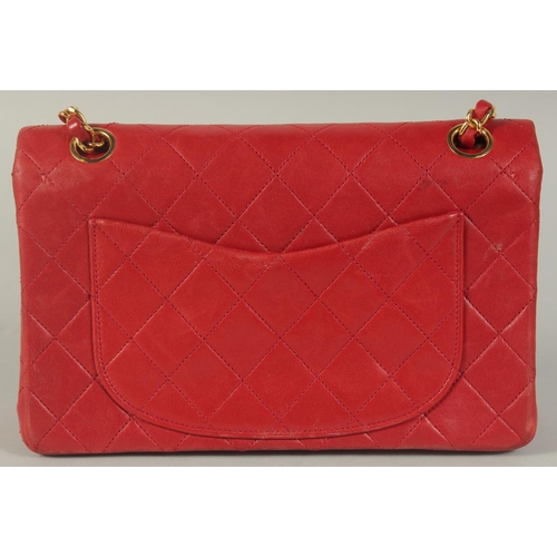 1344 - A CHANEL PADDED LEATHER RED HANDBAG, with entwined leather and gilt straps. 9ins wide.