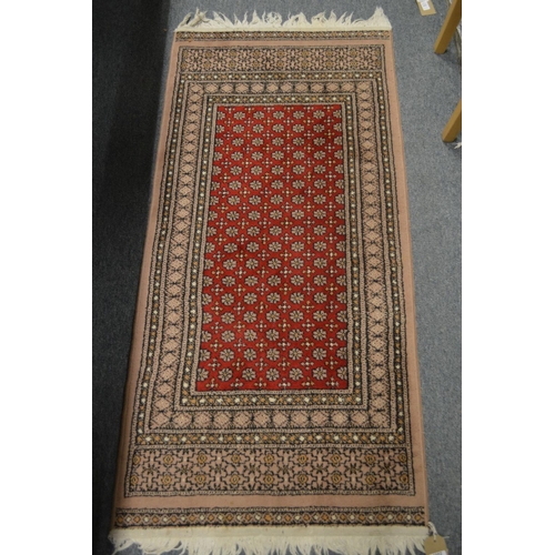 1002 - A SMALL MODERN PERSIAN DESIGN RUG, red ground with stylised decoration. 144cm x 66cm.