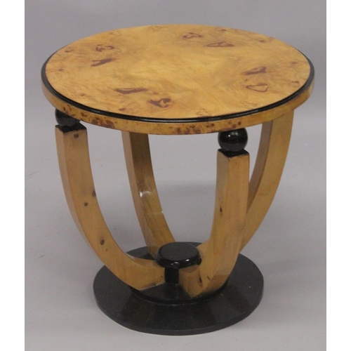 1046 - AN ART DECO STYLE BLONDWOOD CIRCULAR TABLE on curving supports. 1ft 10ins high x 2ft 11ins diameter.... 