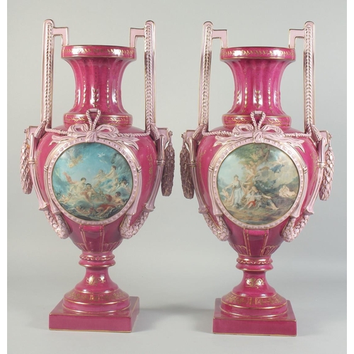 1126 - A LARGE PAIR OF BURGUNDY SEVRES STYLE TWO HANDLED URNS with circular classical scenes. 1ft 11ins hig... 