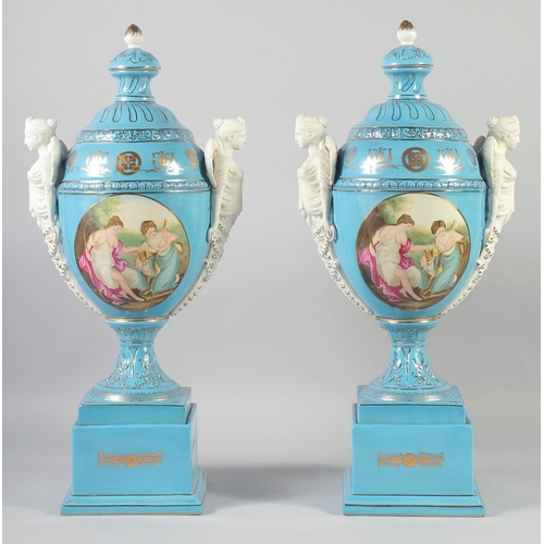 1127 - A LARGE PAIR OF CONTINENTAL LIGHT BLUE TWO HANDLED URNS AND COVERS with classical female heads, on s... 