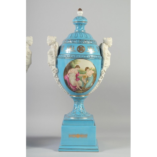 1127 - A LARGE PAIR OF CONTINENTAL LIGHT BLUE TWO HANDLED URNS AND COVERS with classical female heads, on s... 