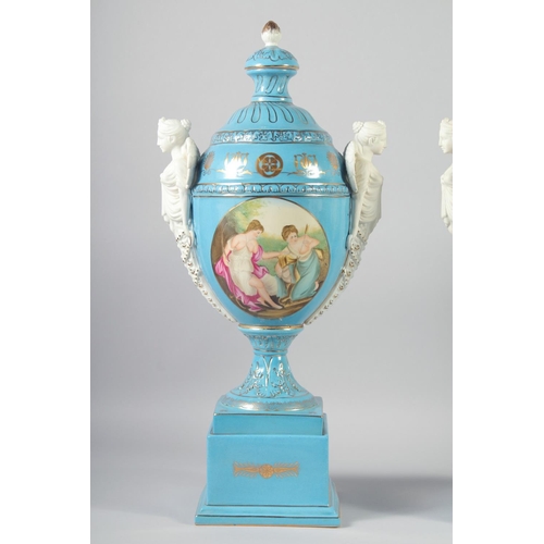 1127 - A LARGE PAIR OF CONTINENTAL LIGHT BLUE TWO HANDLED URNS AND COVERS with classical female heads, on s... 