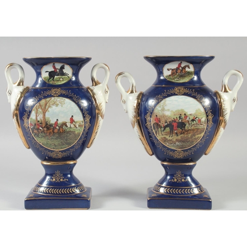 1128 - A PAIR OF CONTINENTAL BLUE TWO HANDLED HUNTING SCENE VASES. 11ins high.