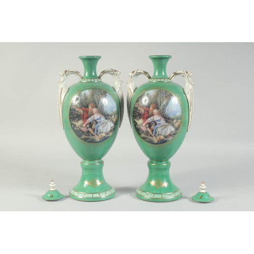 1130 - A PAIR OF GREEN GROUND SEVRES STYLES TWO HANDLED VASES AND COVERS with oval classical scenes. 1ft 3i... 