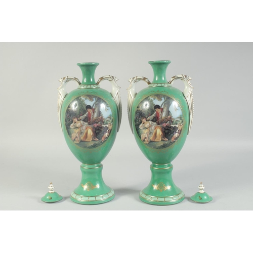 1130 - A PAIR OF GREEN GROUND SEVRES STYLES TWO HANDLED VASES AND COVERS with oval classical scenes. 1ft 3i... 