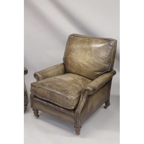 1008 - A SUPERB PAIR OF LEATHER ARMCHAIRS  with brass studs on turned legs, with brass casters. 2ft 8ins wi... 