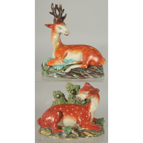 1063 - TWO LARGE STAFFORDSHIRE SEATED DEER with spots on rustic bases 7ins & 4.5ins.