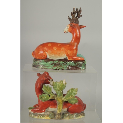 1063 - TWO LARGE STAFFORDSHIRE SEATED DEER with spots on rustic bases 7ins & 4.5ins.