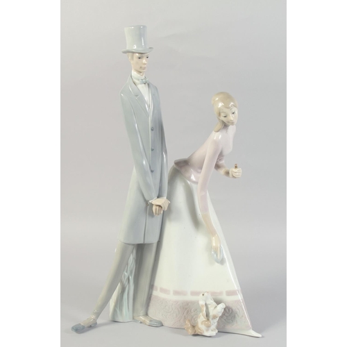 1070 - A LARGE LLADRO PORCELAIN GROUP, TWO LONG FIGURES, a dog at their feet. 20ins high.