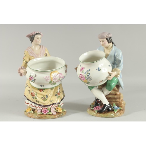 1083 - A PAIR OF SEVRES DESIGN PORCELAIN FIGURES OF A MAN AND WOMAN HOLDING BOWLS, the bases with flowers. ... 