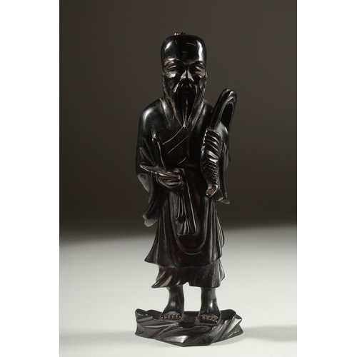 149 - A CHINESE BAKELITE FIGURE on a fitted wooden stand, figure 15cm high.