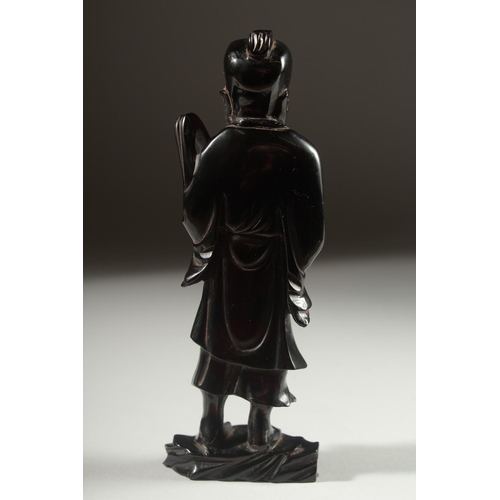 149 - A CHINESE BAKELITE FIGURE on a fitted wooden stand, figure 15cm high.