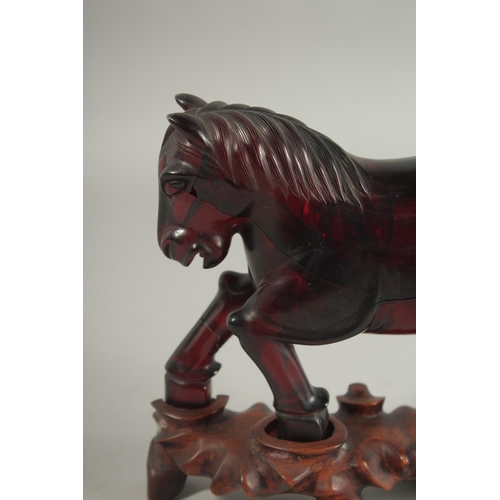 150 - A RARE CHINESE BAKELITE -POSSIBLY CHERRY AMBER HORSE on original wooden stand, horse 21cm long, weig... 