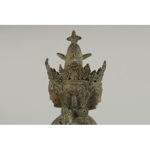 179 - A FIGURE OF A SEATED MULTI-HEADED DEITY, 22cm high.