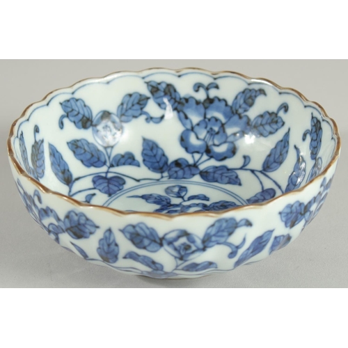 18 - A CHINESE BLUE AND WHITE PORCELAIN BOWL, with ribbed exterior and petal form rim, decorated with flo... 