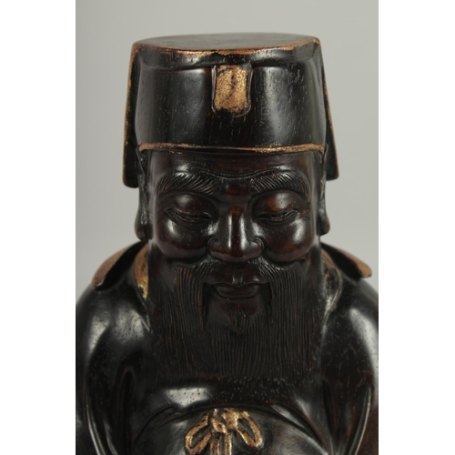 187 - A FINE CHINESE CARVED HARDWOOD FIGURE OF A SEATED IMMORTAL, with painted gilt highlights, the revers... 