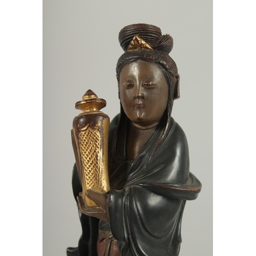 189 - A LACQUERED AND GILDED CARVED WOODEN  FIGURE, of Guanyin holding an urn, 17cm high.