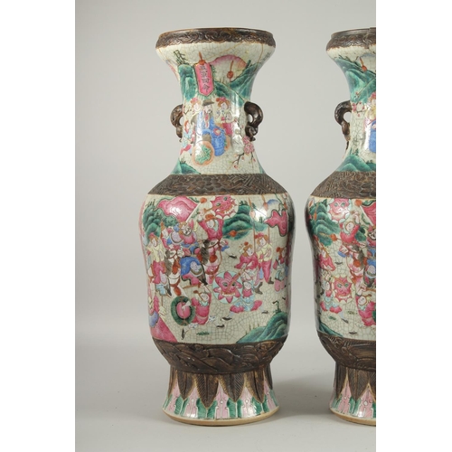 201 - A LARGE PAIR OF CHINESE FAMILLE ROSE PORCELAIN VASES, with moulded twin handles, each painted with a... 