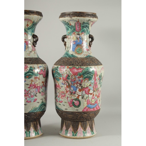 201 - A LARGE PAIR OF CHINESE FAMILLE ROSE PORCELAIN VASES, with moulded twin handles, each painted with a... 