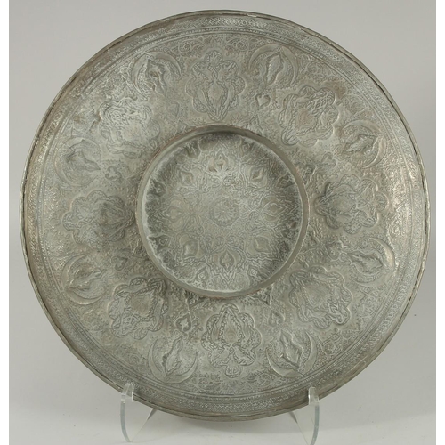 296 - A LARGE QAJAR EMBOSSED AND CHASED WHITE METAL DISH, 48.5cm diameter.